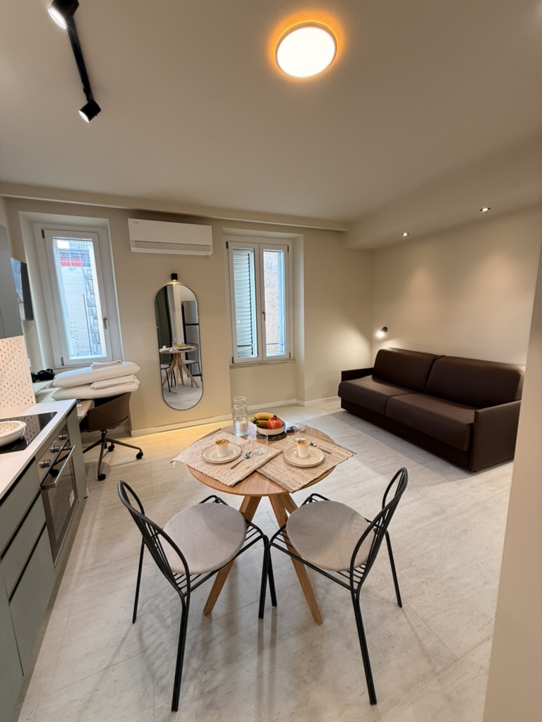 Monolocale Verde: living area with sofa, round dining table and two windows